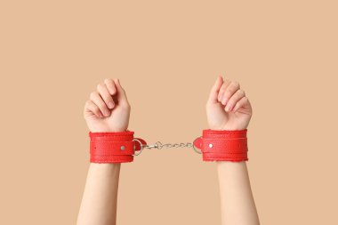 Seks dükkanından gelen kırmızı kelepçeli kadın elleri. Arka planda, yakın plan.