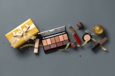Gri arka planda Noel dekoru ve kozmetik ürünleri içeren kompozisyon
