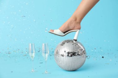 Disko toplu kadın bacağı ve mavi arka planda şampanya bardakları.