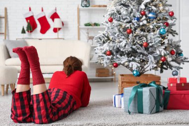 Güzel genç bir kadın Noel süsü verilmiş bir odada yatıyor.