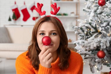 Geyik boynuzları ve süslü odada Noel balosu olan güzel genç bir kadın.