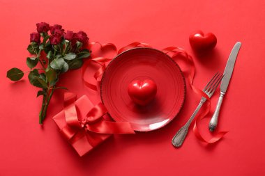 Kırmızı arka planda sevgililer günü için gül ve hediyeli güzel bir masa.
