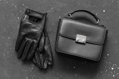 Siyah arka planda kadın deri eldivenler ve el çantası.