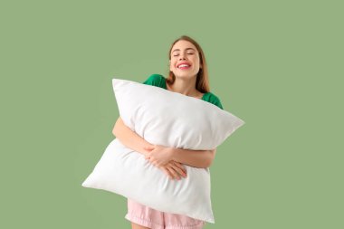 Yeşil arka planda beyaz yumuşak yastıklı güzel bir genç kadın.