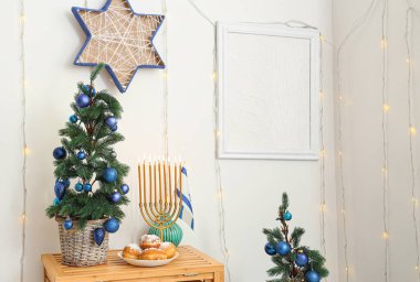 Wooden table with fir tree, menorah and sufganiyots in living room clipart