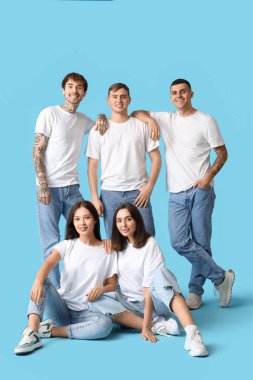 Mavi arka planda şık kotlu bir grup genç.