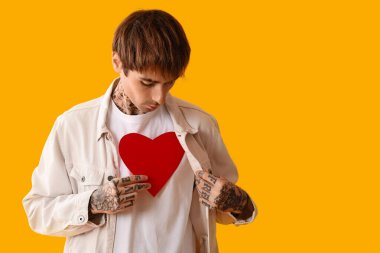 Sarı arka planda kırmızı kağıt kalpli genç adam.