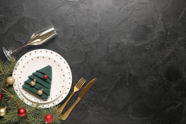 Köknar dalları ve siyah arka planda Noel topları olan güzel bir masa.