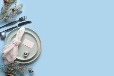 Köknar dalları, Noel topları ve mavi arka planda çam kozalakları olan güzel bir masa.