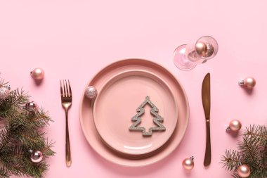 Köknar dallarıyla güzel bir masa ve pembe arka planda Noel topları.