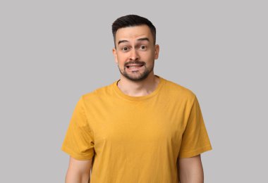 Gri arka plandaki yakışıklı, endişeli genç adam.