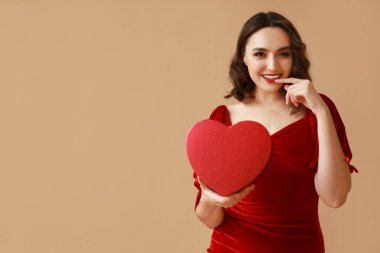 Kahverengi arka planda hediye kutusu olan mutlu genç bir kadın.