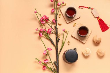 Çay fincanları, fal kurabiyeleri ve bej arkaplanda Çince semboller olan Sakura. Yeni yıl kutlaması