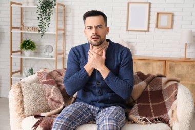 Hasta genç adam evdeki kanepede oturuyor.