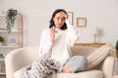 Evdeki kanepede oturan genzinden damlalar akan hasta genç kadın.