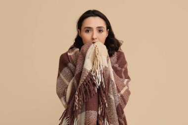 Bej arka planda ekoseli hasta genç bir kadın.