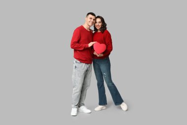 Gri arka planda hediye kutusu olan sevgi dolu genç bir çift. Sevgililer Günü 'nün kutlaması