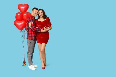 Mavi arka planda kalp şeklinde balonları olan sevgi dolu genç bir çift. Sevgililer Günü 'nün kutlaması