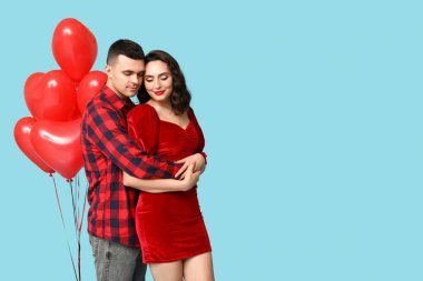 Mavi arka planda kalp şeklinde balonları olan sevgi dolu genç bir çift. Sevgililer Günü 'nün kutlaması