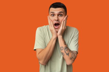 Turuncu arka planda yakışıklı bir genç adam.