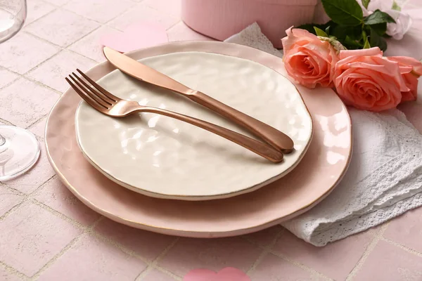 Beautiful table setting with roses for Valentine\'s Day on pink tile background