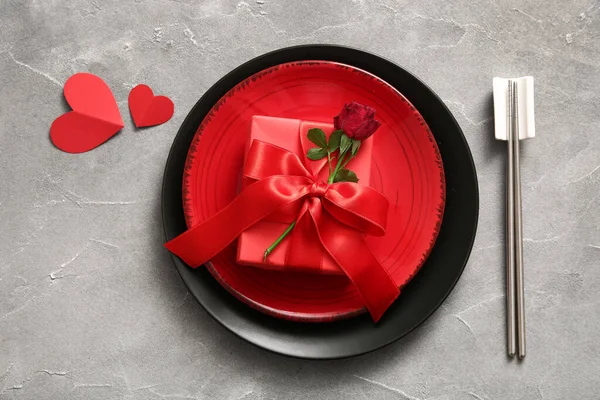 Beautiful table setting with rose and gift for Valentine's Day on grey grunge background