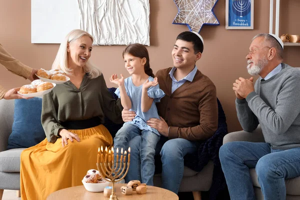 Happy Jewish family with donuts celebrating Hanukkah at home