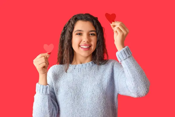 赤い背景に紙のハートを持つ幸せな若い女性 — ストック写真