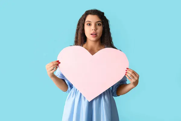 青い背景にピンクの紙の心を持つ美しい若い女性 — ストック写真