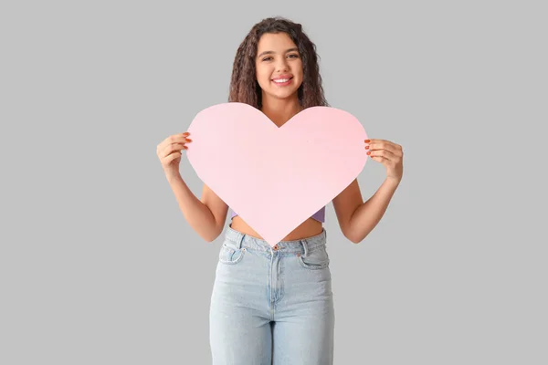 灰色の背景にピンクの紙の心を持つ幸せな若い女性 — ストック写真