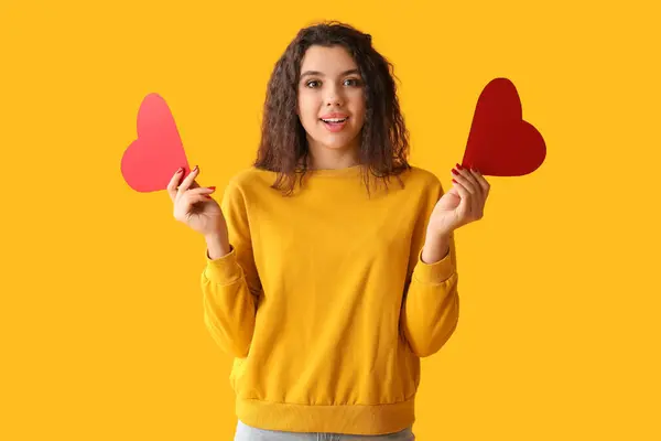 黄色の背景に赤い紙の心を持つ美しい若い女性 — ストック写真