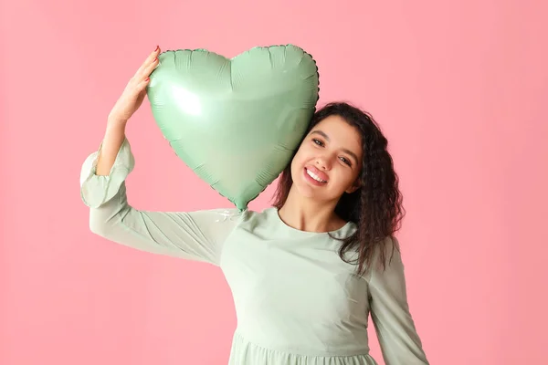 ピンクの背景に心臓形のエアバルーンを持つ幸せな若い女性 — ストック写真