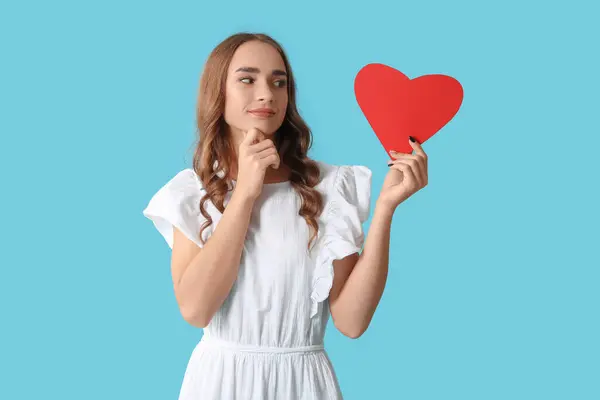 Mujer Joven Pensativa Con Corazón Papel Rojo Sobre Fondo Azul — Foto de Stock