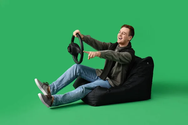 Junger Mann Mit Lenkrad Zeigt Auf Etwas Auf Grünem Hintergrund — Stockfoto