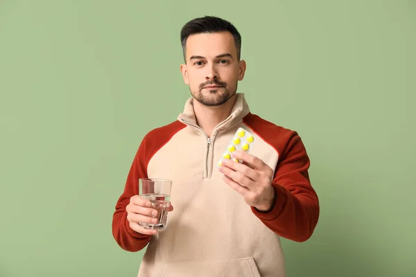 Kranker Junger Mann Mit Pillen Und Glas Wasser Auf Grünem — Stockfoto