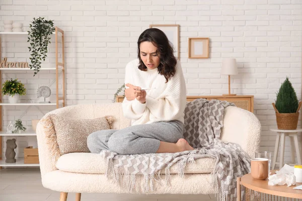 stock image Sick young woman with thermometer at home