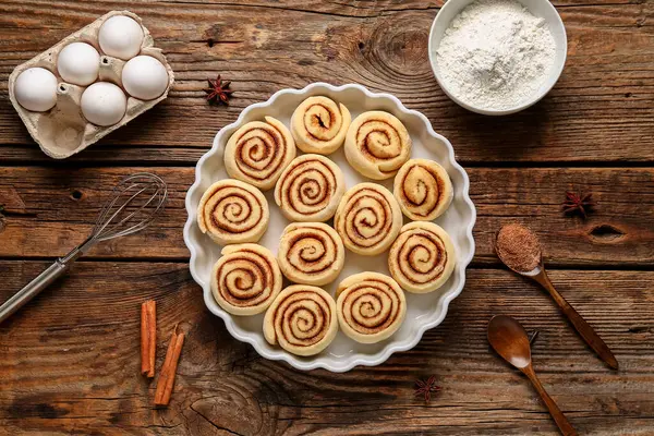 Pişmemiş tarçınlı yemek tabağı ve ahşap arka planda malzemeler.