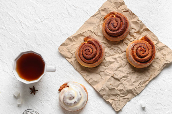 Tasty cinnamon rolls and cup of tea on white background