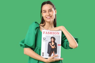 Yeşil arka planda moda dergisiyle genç bir kadın.