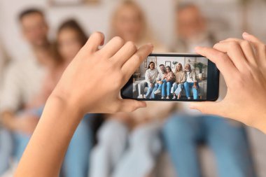 Cep telefonlu küçük bir çocuk büyük ailesinin fotoğrafını çekiyor.