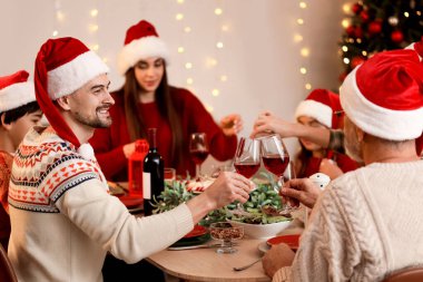 Genç bir adam akşam ailesiyle Noel yemeği yiyor.