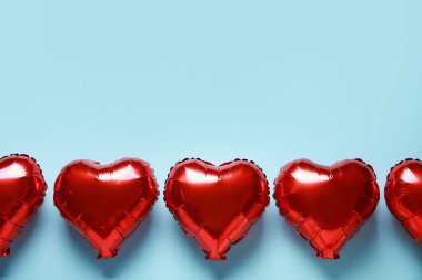 Kırmızı kalp şekilli hava balonları mavi arka planda
