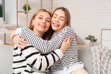 Evdeki kanepede annesine sarılan mutlu genç bir kadın. Uluslararası Sarılma Günü