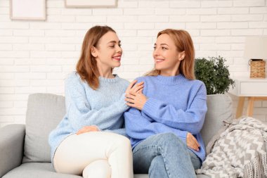 Evdeki kanepede güzel bir genç kadın ve annesi. Uluslararası Sarılma Günü