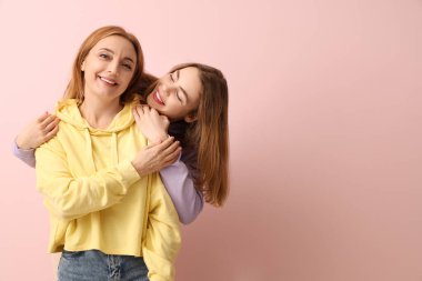 Güzel genç bir kadın pembe arka planda annesine sarılıyor. Uluslararası Sarılma Günü