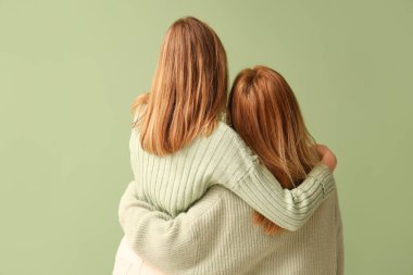 Yeşil arka planda annesine sarılan genç bir kadın. Uluslararası Sarılma Günü