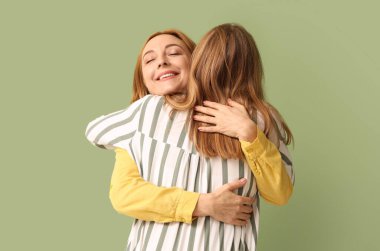 Olgun bir kadın yeşil arka planda genç kızına sarılıyor. Uluslararası Sarılma Günü