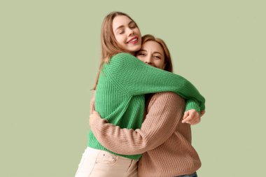 Mutlu genç bir kadın yeşil arka planda annesine sarılıyor. Uluslararası Sarılma Günü