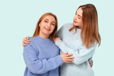 Güzel genç bir kadın mavi arka planda mutlu annesine sarılıyor. Uluslararası Sarılma Günü