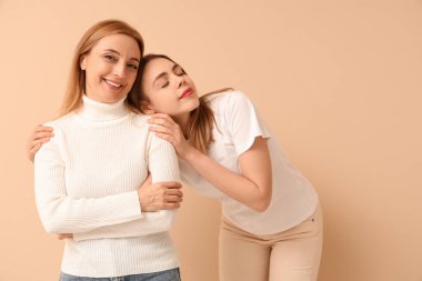 Bej arka planda annesine sarılan güzel bir genç kadın. Uluslararası Sarılma Günü